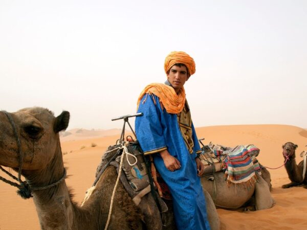 a man sitting on a camel in the desert