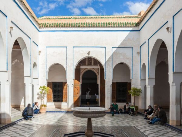a courtyard with a fountain and people sitting on the ground