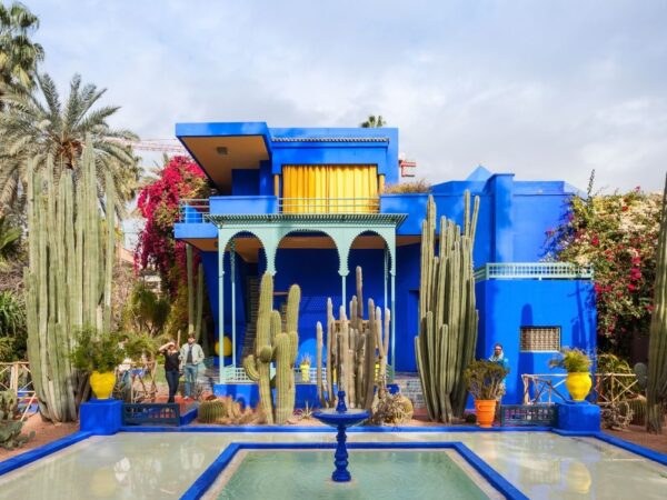 a blue house with a fountain and cacti