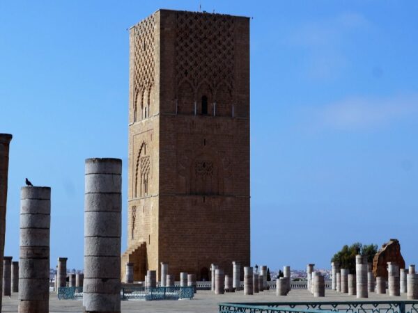 a stone tower with columns in the middle with Hassan Tower in the background